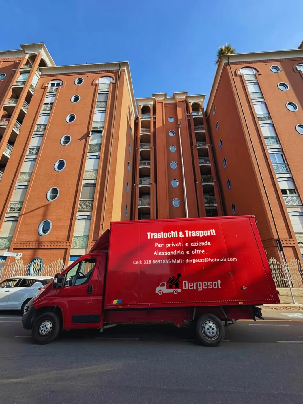 Furgone rosso Dergesat per traslochi davanti a un condominio